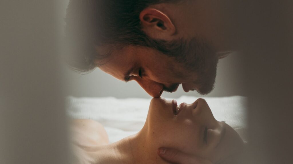 homem por cima beijando mulher 