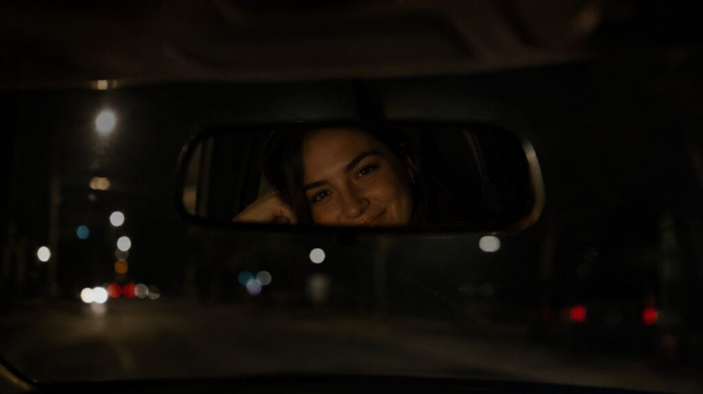 mulher sorrindo no retrovisor do carro