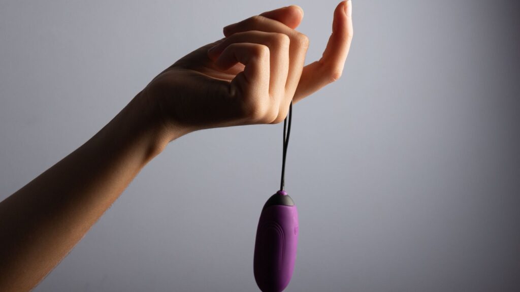 mãe de mulher segurando vibrador bullet roxo