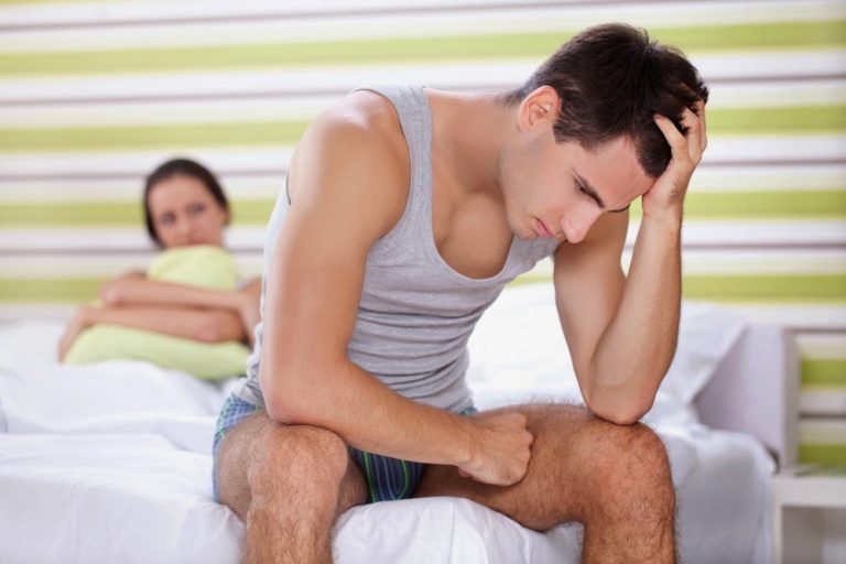 Homem sentado com parceira na cama lidando com a satiríase.