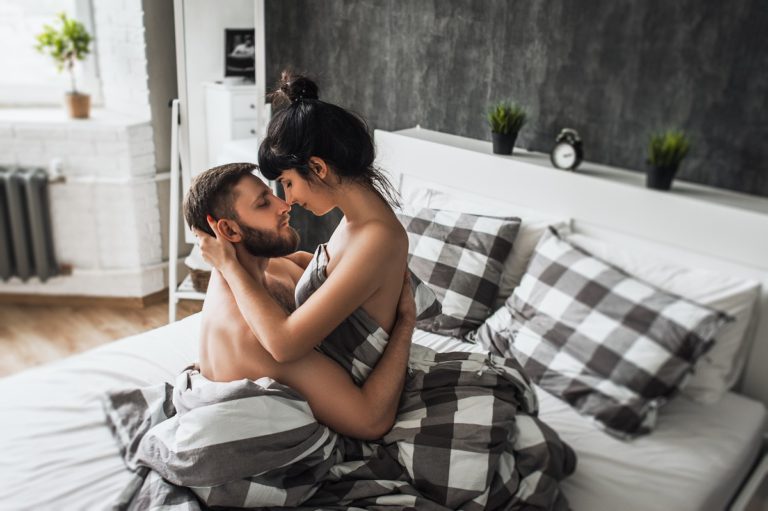 imagem de uma mulher sentada no colo do parceiro na cama