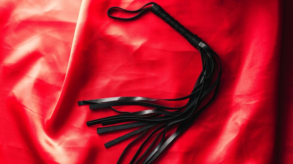 chicote preto em cima de lençol vermelho