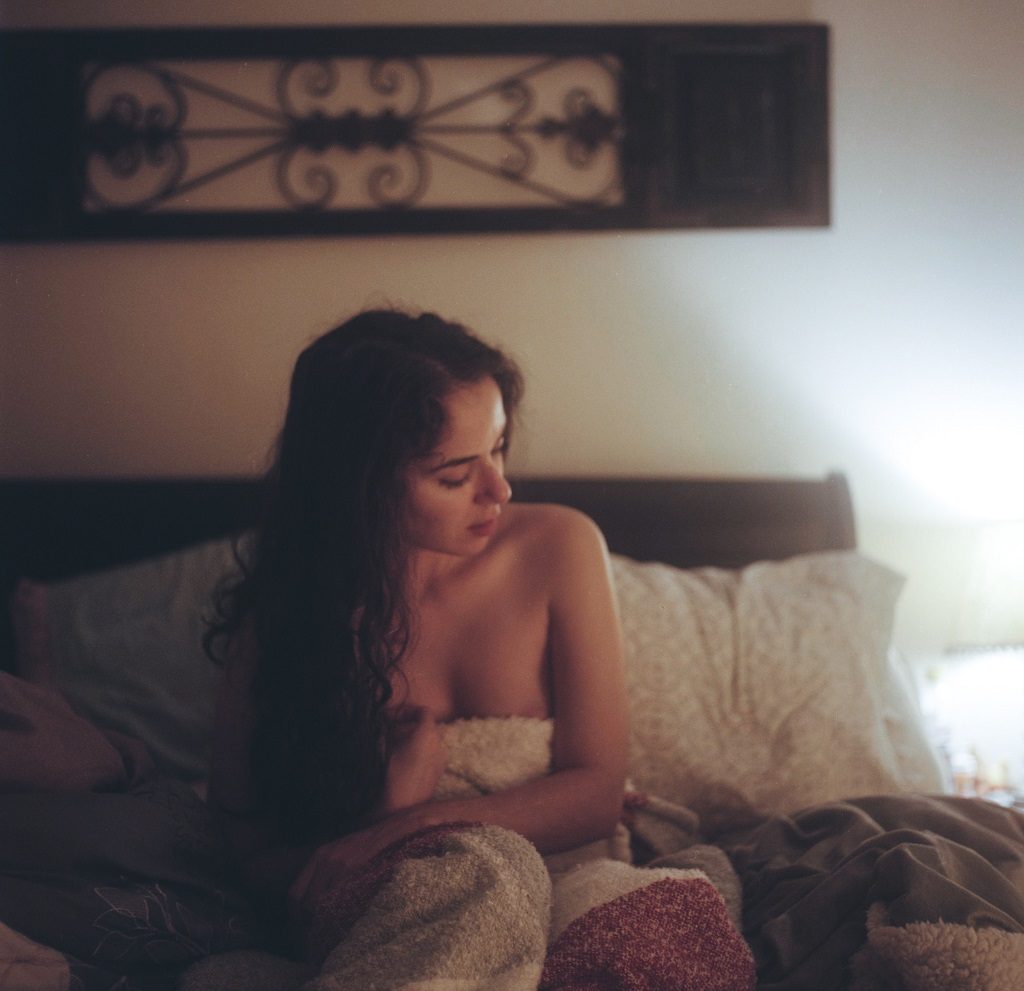 Mulher na cama sozinha experimentando técnicas de pompoarismo