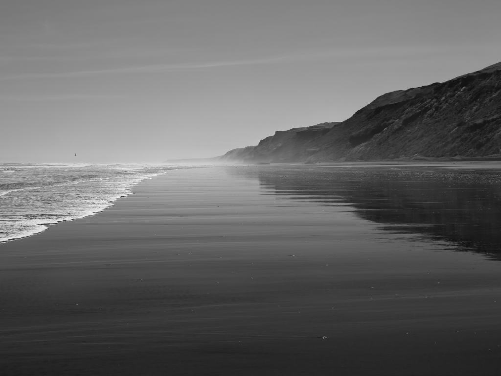 praia com uma montanha em preto e branco