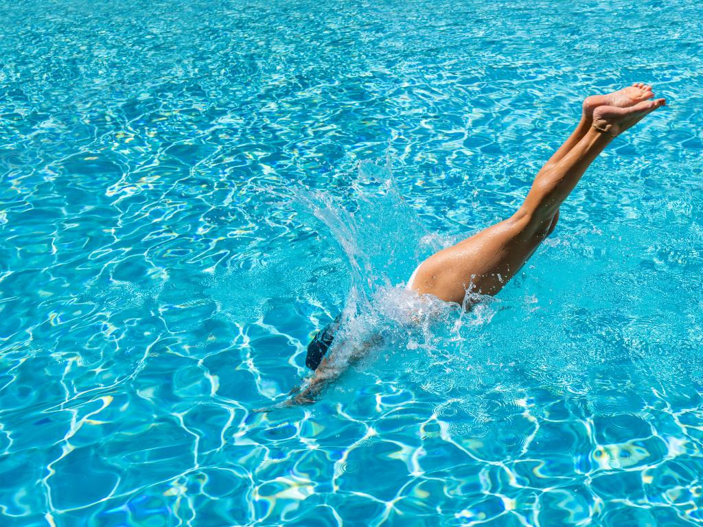 mulher mergulhando no mar com água azul