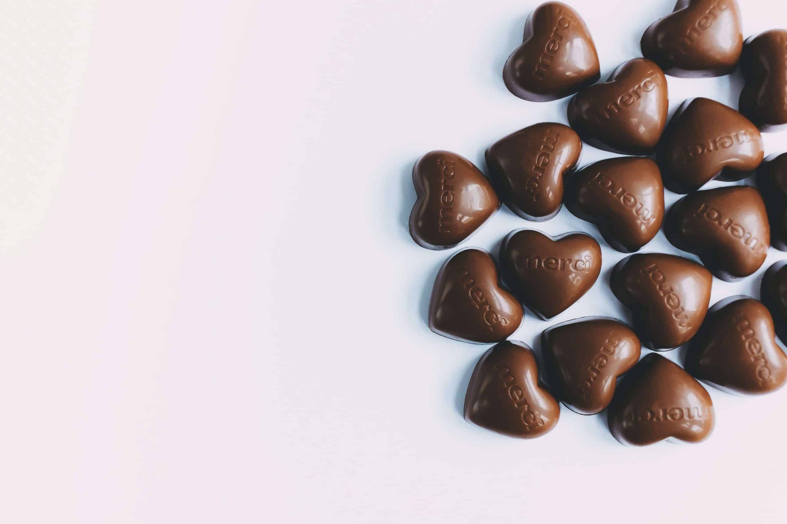 Bombons de chocolate em formato de coração, em um fundo branco.