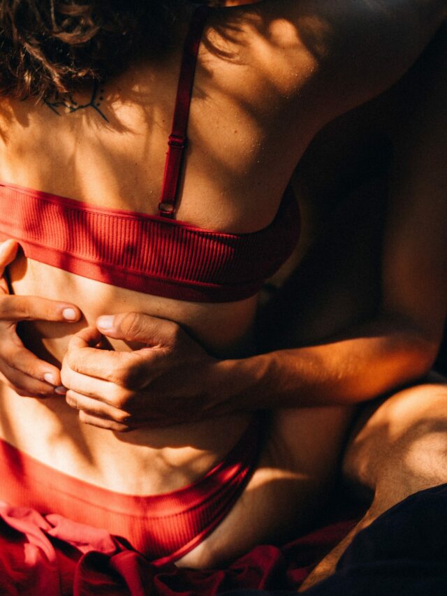Mulher vestindo lingerie vermelha, abraçada com um homem