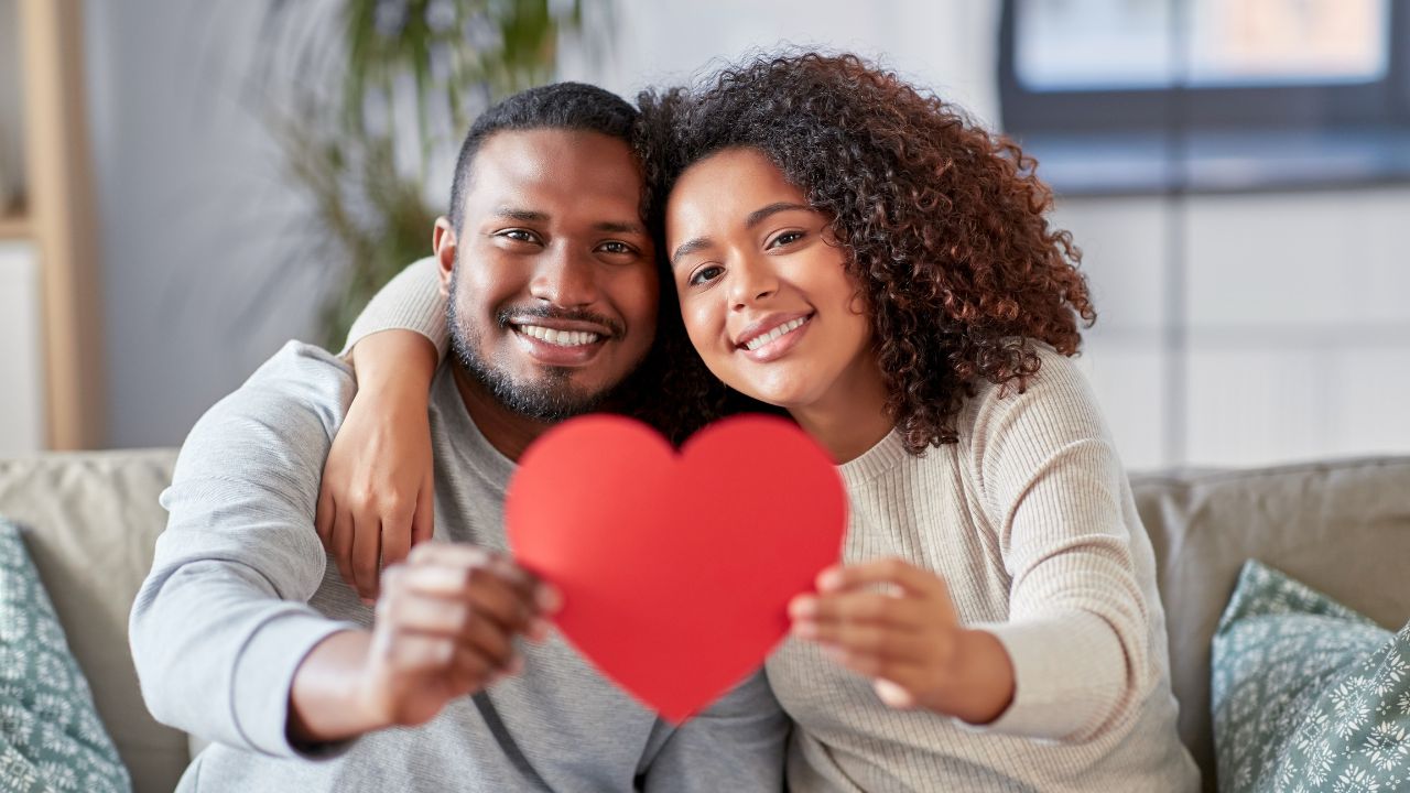 casal negro segurando um papel vermelho em formato de coração