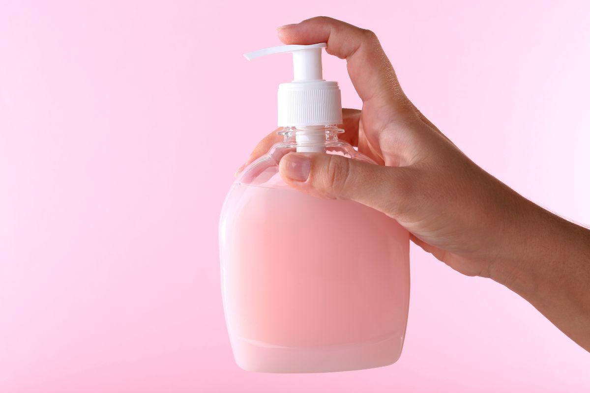 imagem de uma mão pressionando um frasco de sabonete íntimo