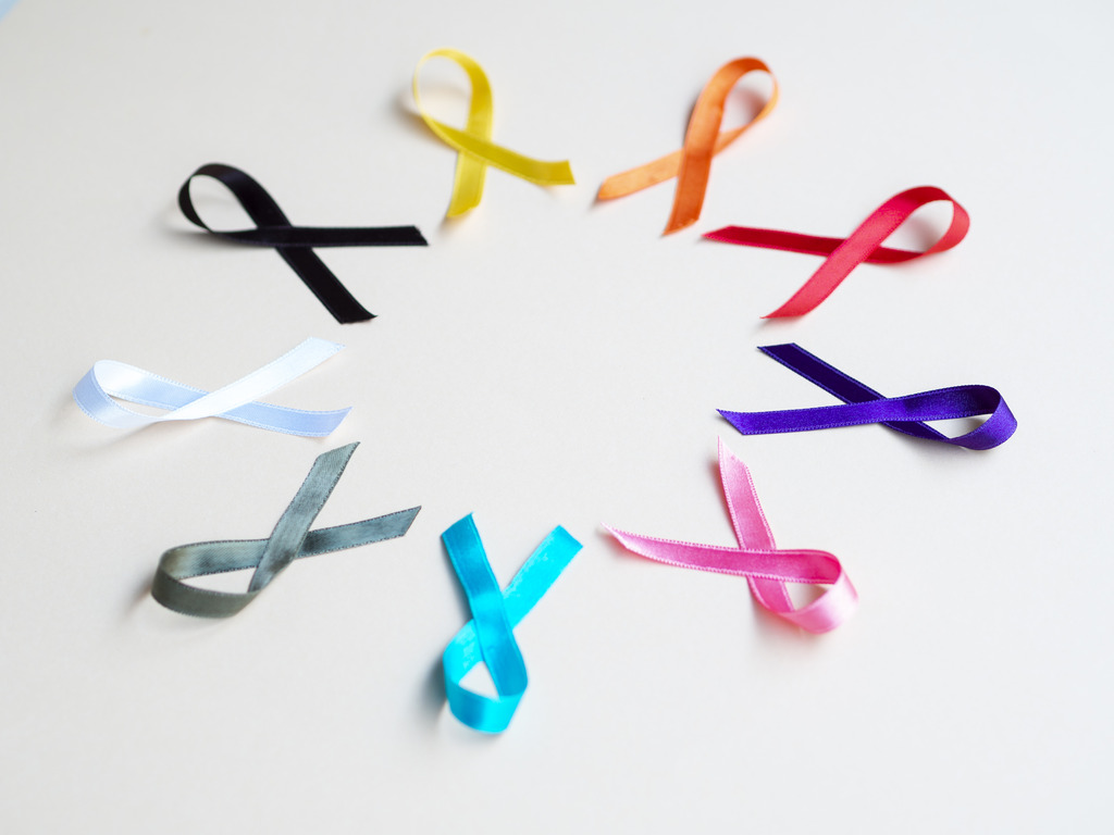 Conjunto de laços de diversas cores, com cada um indicando um tipo de câncer, colocados em círculo.