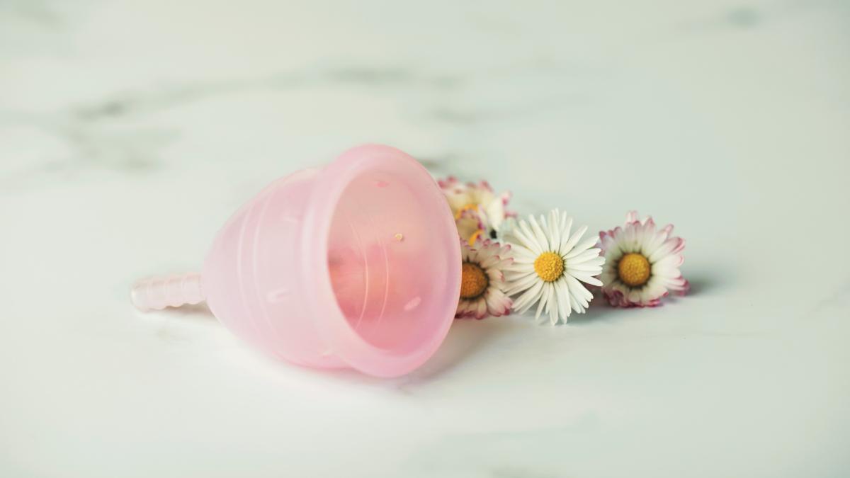 Coletor menstrual ao lado de flores.