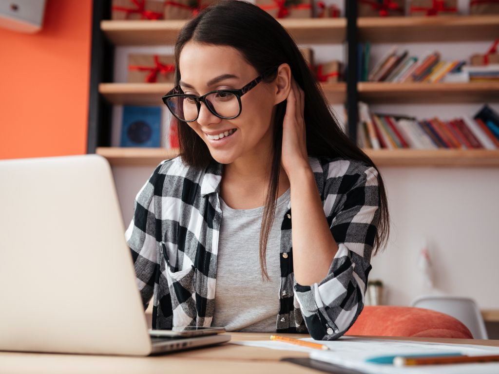 mulher sorrindo olhando para um computador para ilustrar um post sobre como revender produtos na shoepe