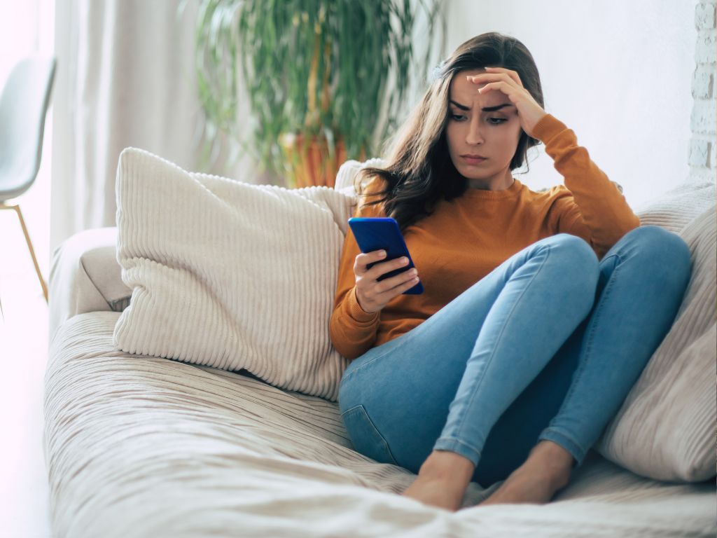 mulher chateada olhando para o celular após sofrer ghosting