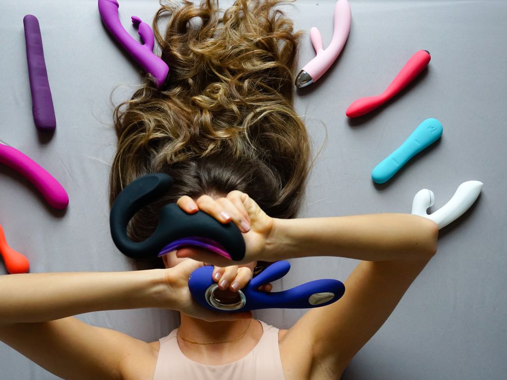 mulher rodeado de vários modelos de vibrador coelhinho