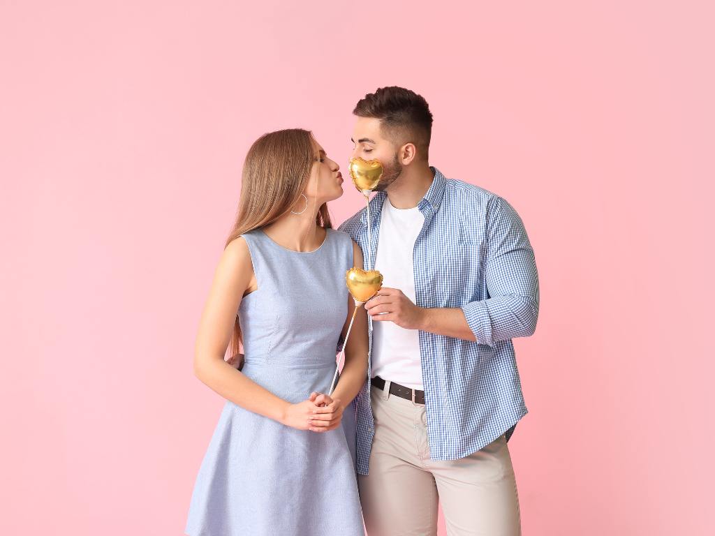 Casal em fundo rosa com balões de coração