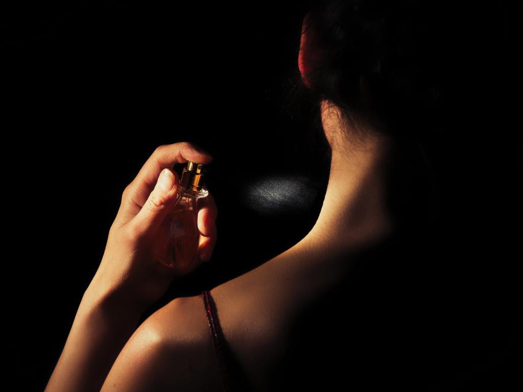 Mulher aplicando perfume no pescoço