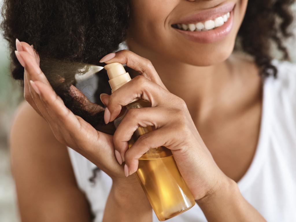 Mulher aplicando óleo no cabelo