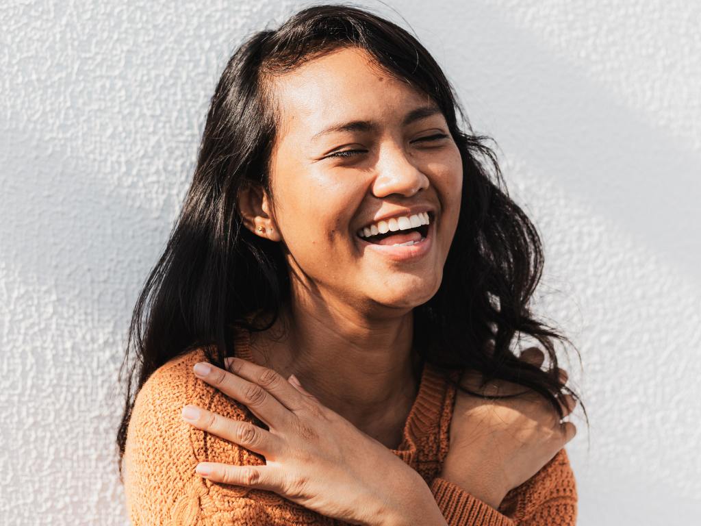 Mulher se abraçando e sorrindo