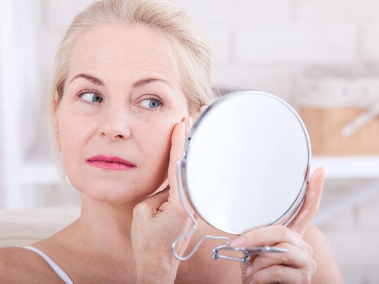 Mulher olhando sua pele no espelho
