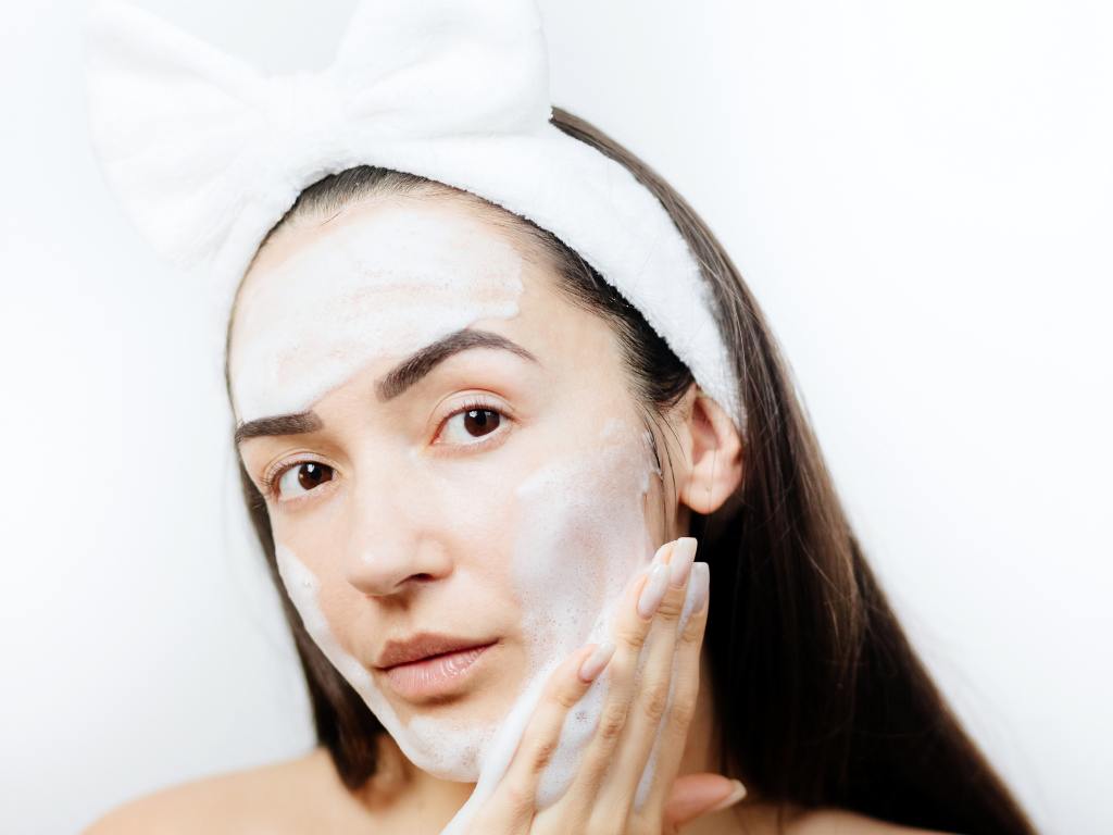 Mulher aplicando sabonete líquido facial