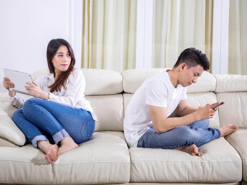 casal no sofá de costas um para o outro com homem praticando traição online