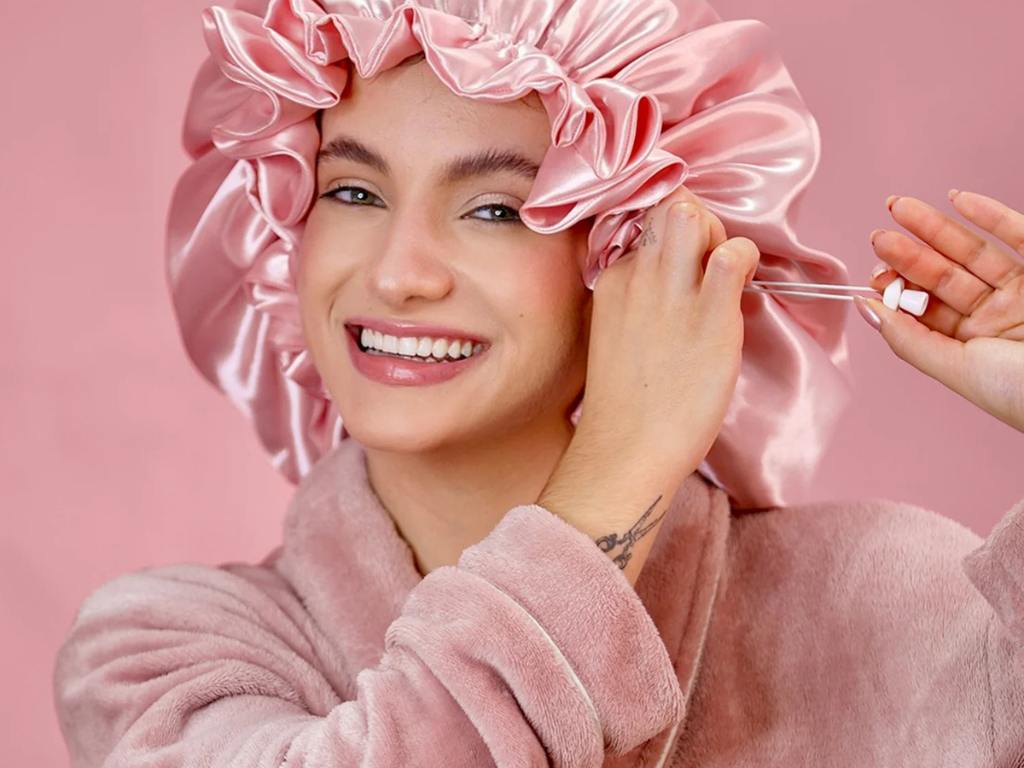 Mulher colocando touca de cetim rosa