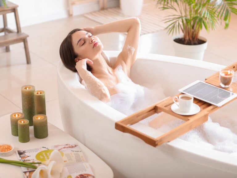 Mulher tomando banho premium com velas, comida e tablet na banheira