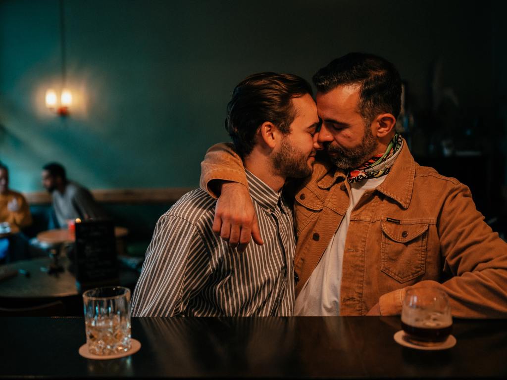 Homens beijando em bar gay