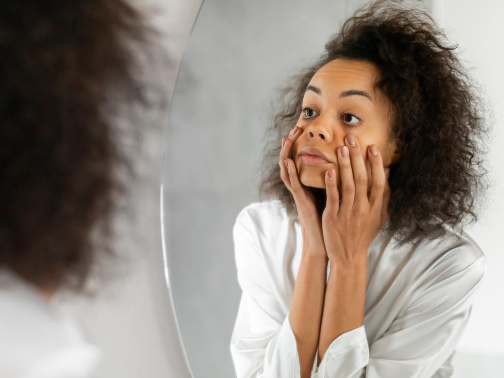 mulher olhando as olheiras no espelho