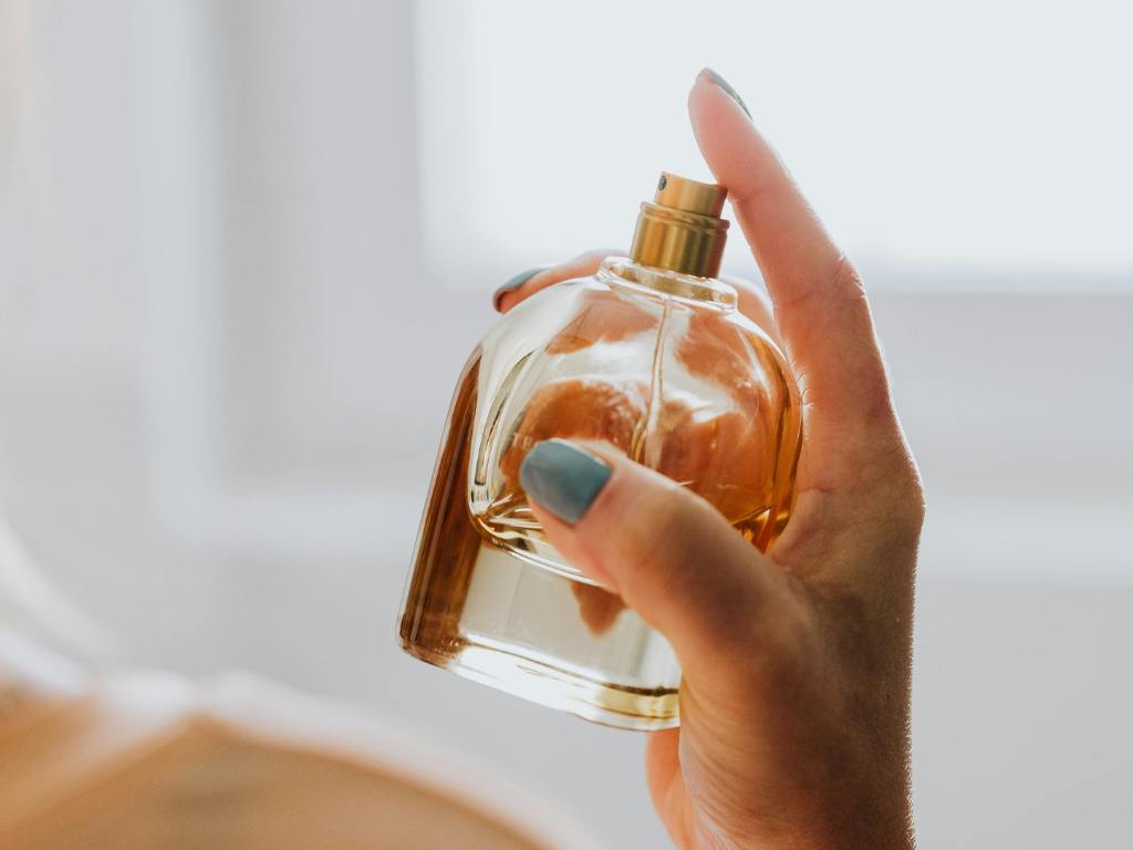 mão espirrando franco de perfume árabe