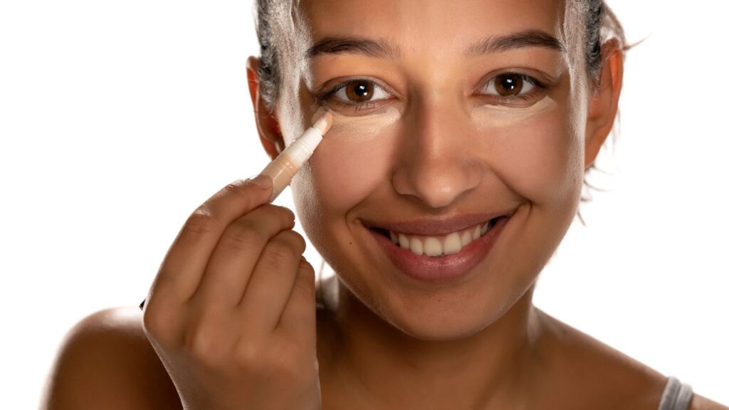 mulher sorrindo aplicando corretivo