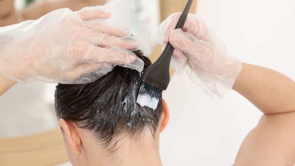 mulher aprendendo como pintar o cabelo em casa passando tinta na região da nuca