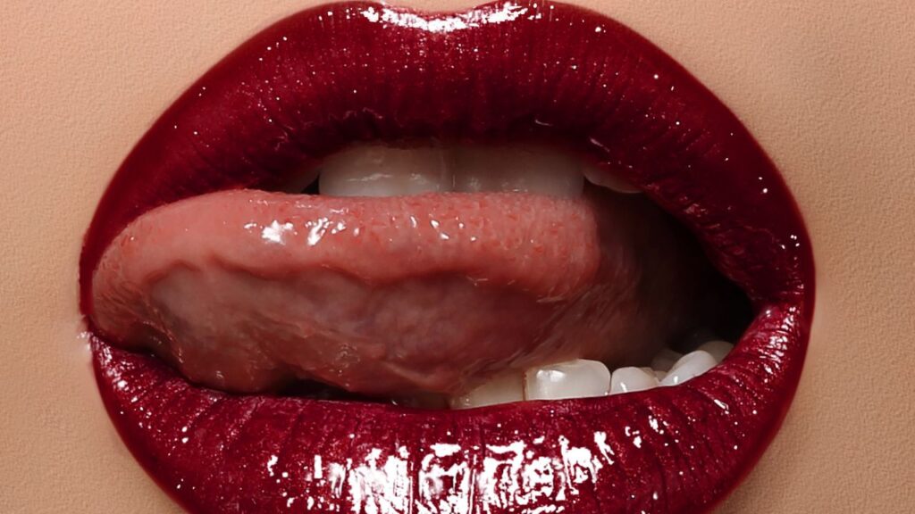 boca com língua para fora de forma sensual e batom vermelho com brilho