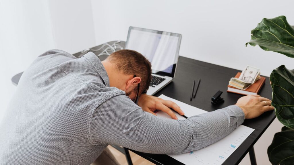 homem cansada deitado na mesa de trabalho