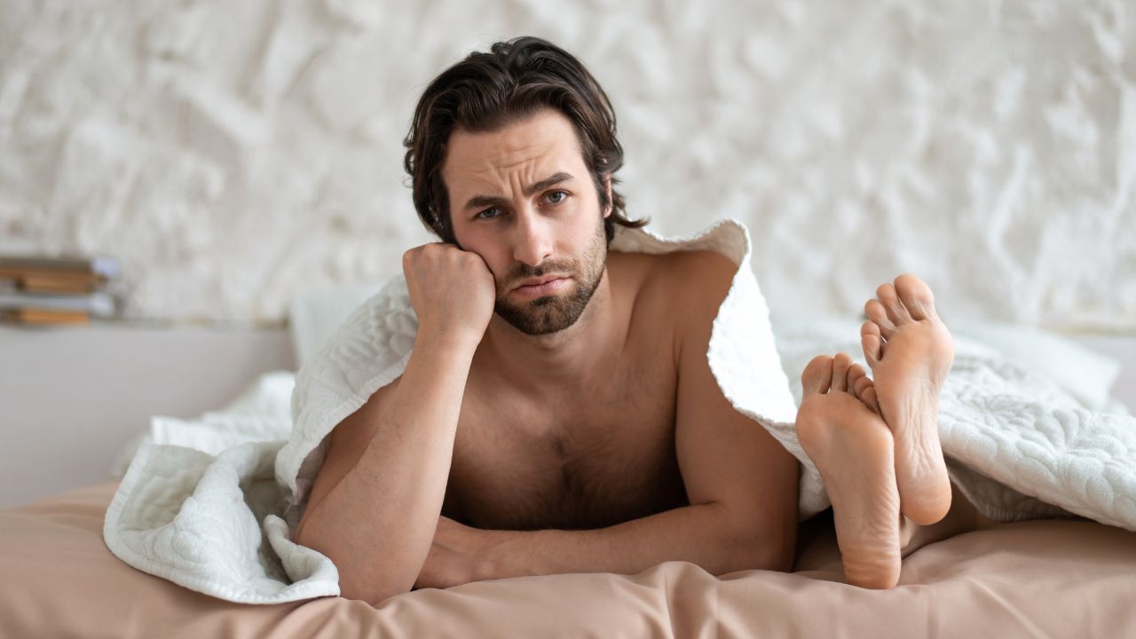 homem triste na cama ou lado de pés de mulher