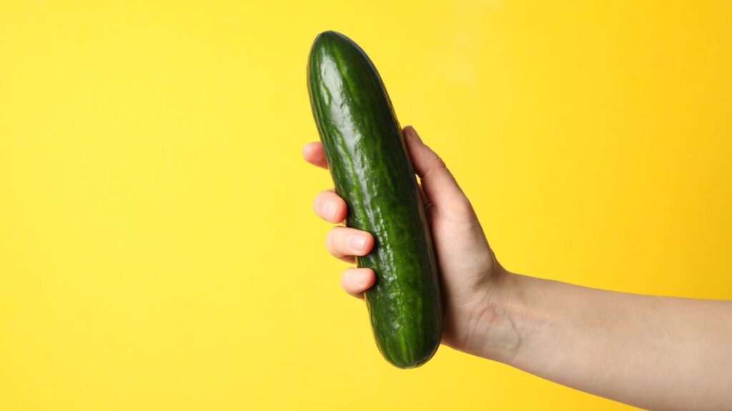 mão segurando pepino representando pênis