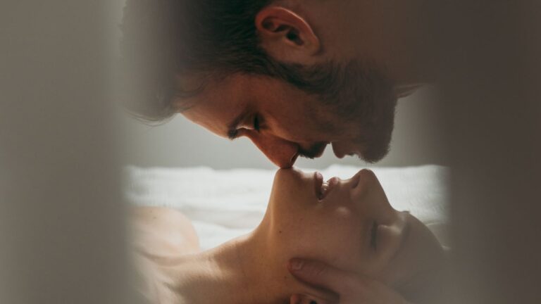 homem por cima e mulher por baixo na cama praticando o beijo arco íris