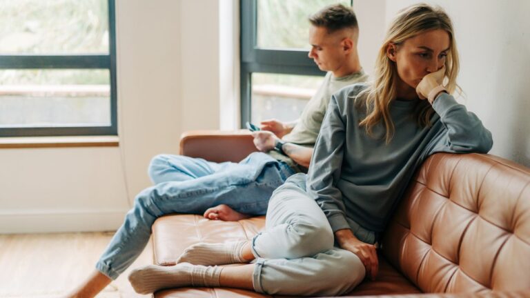 casal no sofá, mulher em primeiro plano com expressão triste com ciúmes retroativo