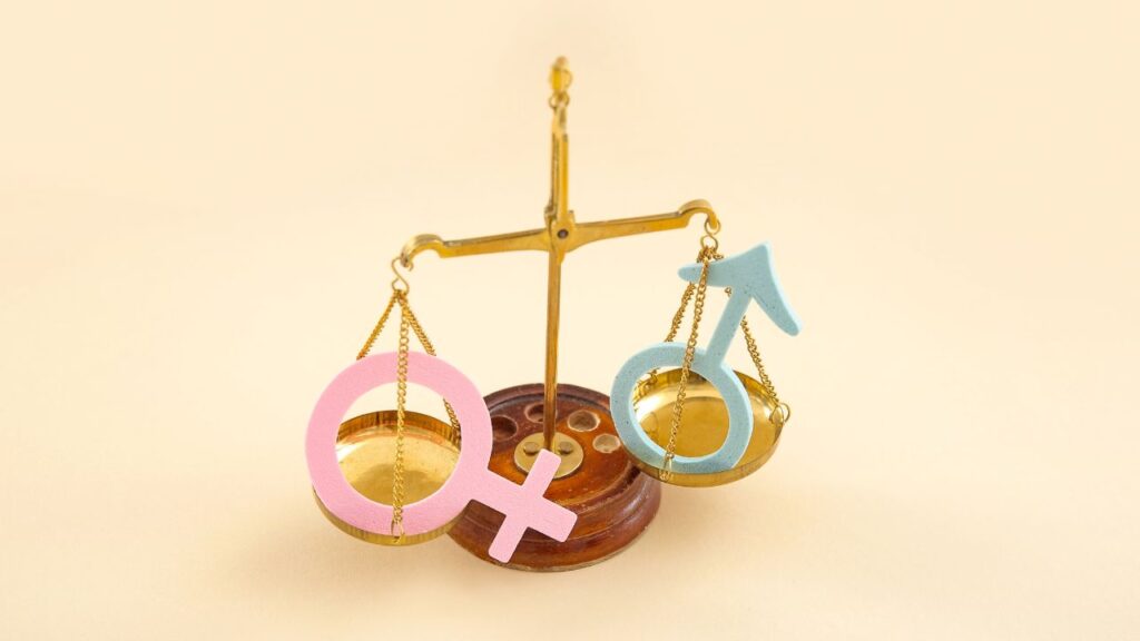 balança com símbolos de homem e mulher para representar igualdade de gênero
