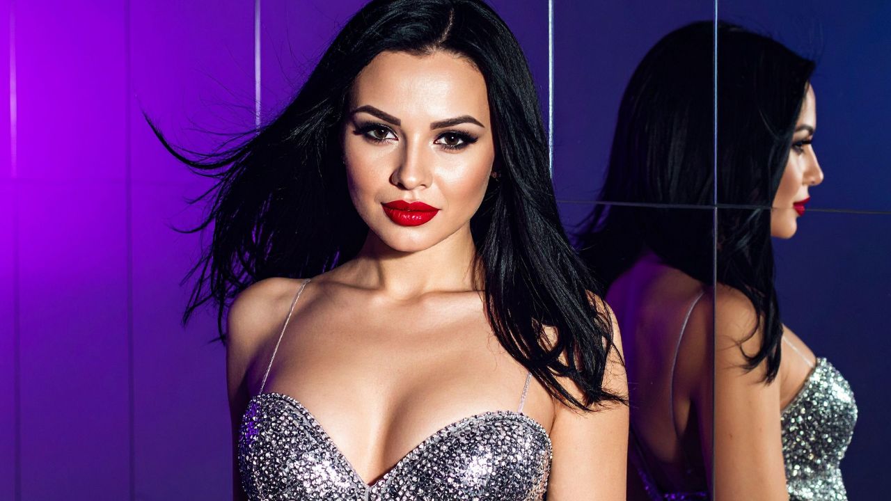 mulher com maquiagem de ano novo com batom vermelho vestindo vestido prateado