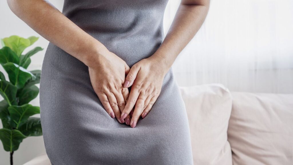 mulher com as mãos na região da vagina com dor devido à fissura vaginal