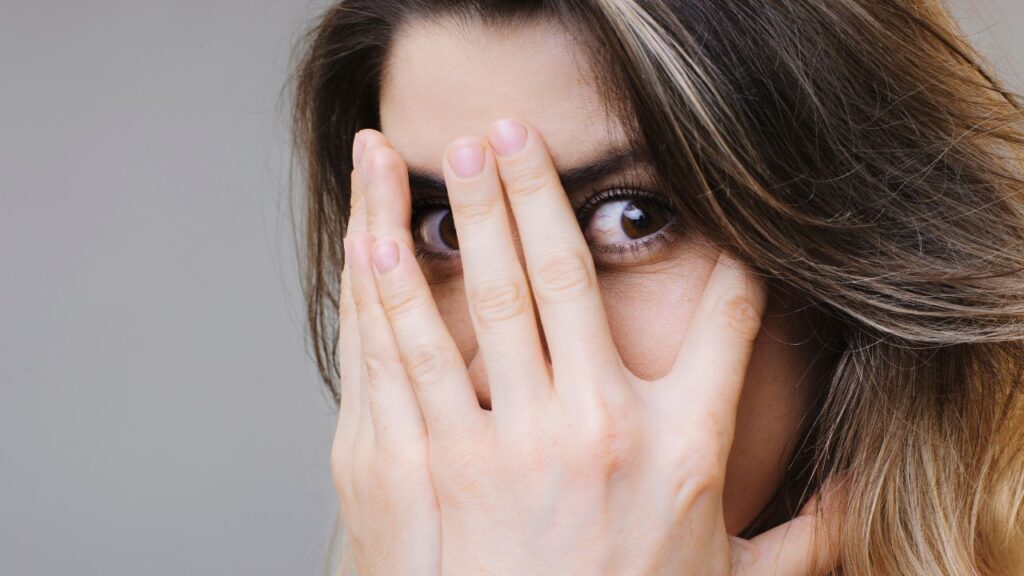 mulher com mãos no rosto e expressão de medo pronta para praticar fear play