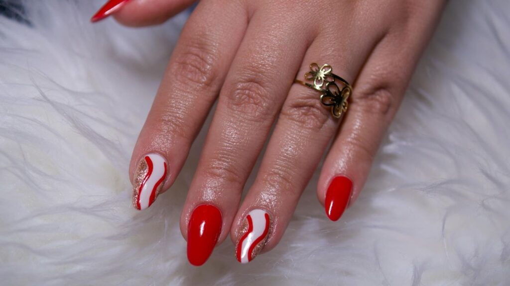 unhas vermelhas com curvas brancas e douradas