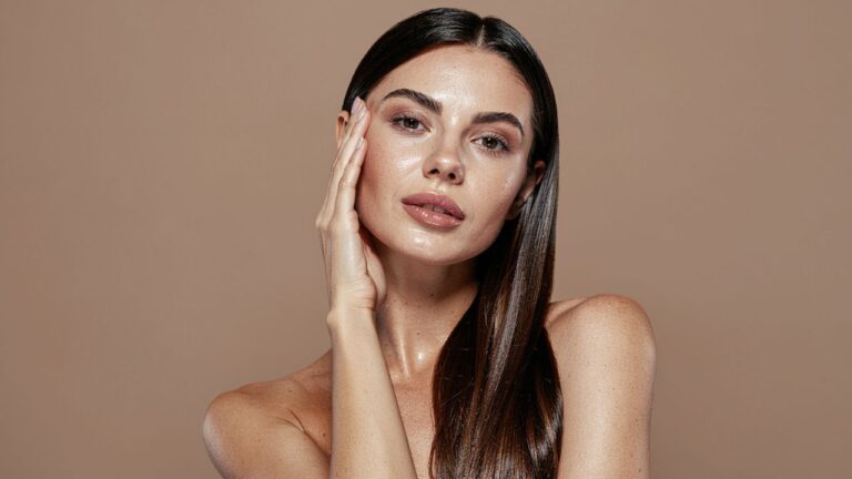 mulher com uma mão no rosto com maquiagem natural e glow