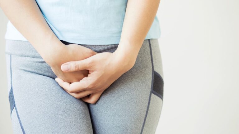 mulher de legging cinza com mãos na região da vagina com corrimento verde