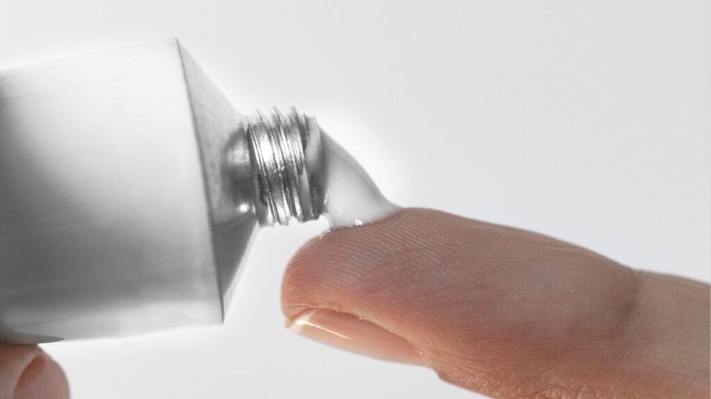 pessoa aplicando pomada no dedo