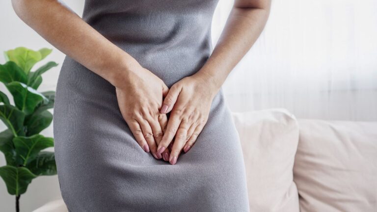 mulher com as mãos na região da área íntima com dor por causa de vagina inchada