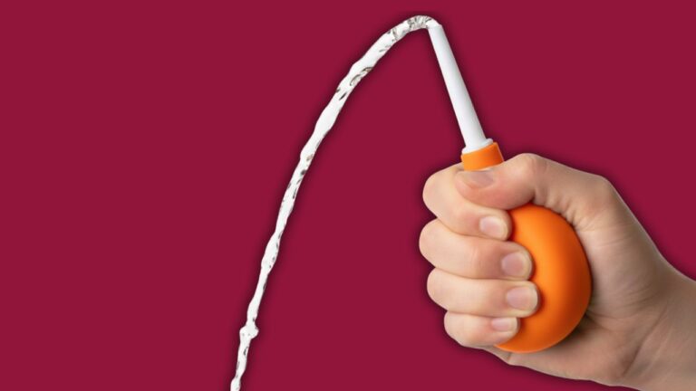 mão segurando acessório de chuca laranja em um fundo bordô