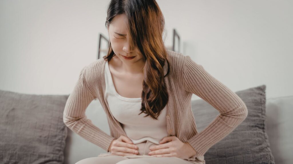 com com expressão de dor segurando a barriga com dor pélvica
