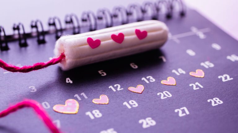 calendário menstrual roxo com dias marcados com coração e ob em cima